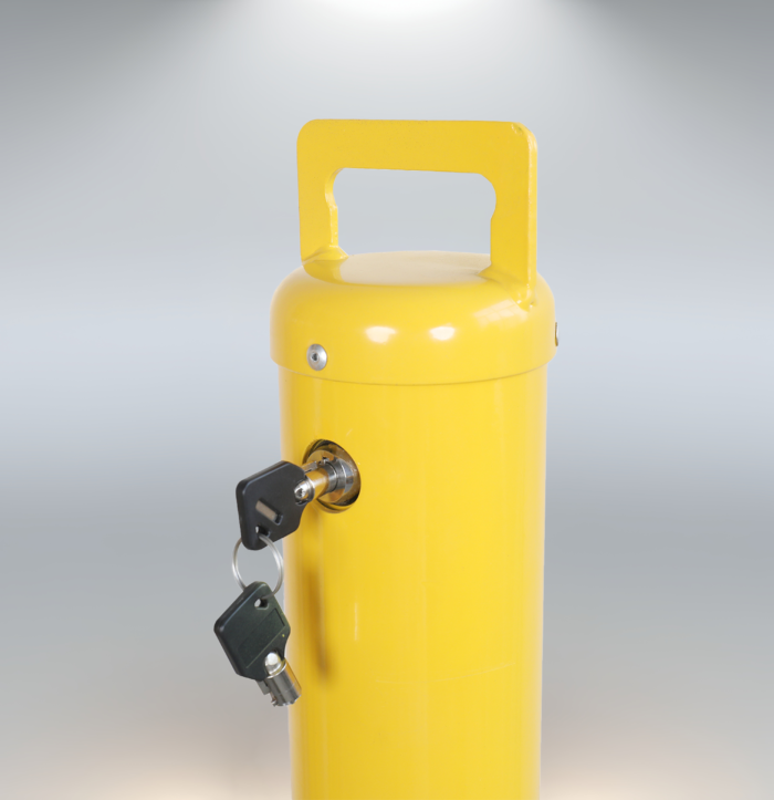 Close-up of lock cylinder and key on removable automatic locking bollard, yellow steel security post with handle.