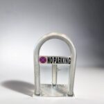 Front view of hot-dip galvanized fold-down parking bollard made of carbon steel, featuring a visible 'NO PARKING' sign to deter vehicle entry.
