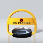 Close-up of solar-powered parking lock, highlighting the bright yellow frame with 'NO PARKING' sign and symbol. Solar panel clearly visible on the black base.