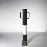Black and white 89-type underground movable bollard with binaural handle, equipped with a bottom padlock to control movement and ensure area security.