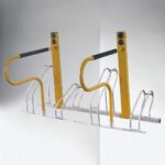 Yellow metal e-bike parking rack with black handles, installed in an outdoor public area for organized bicycle parking.