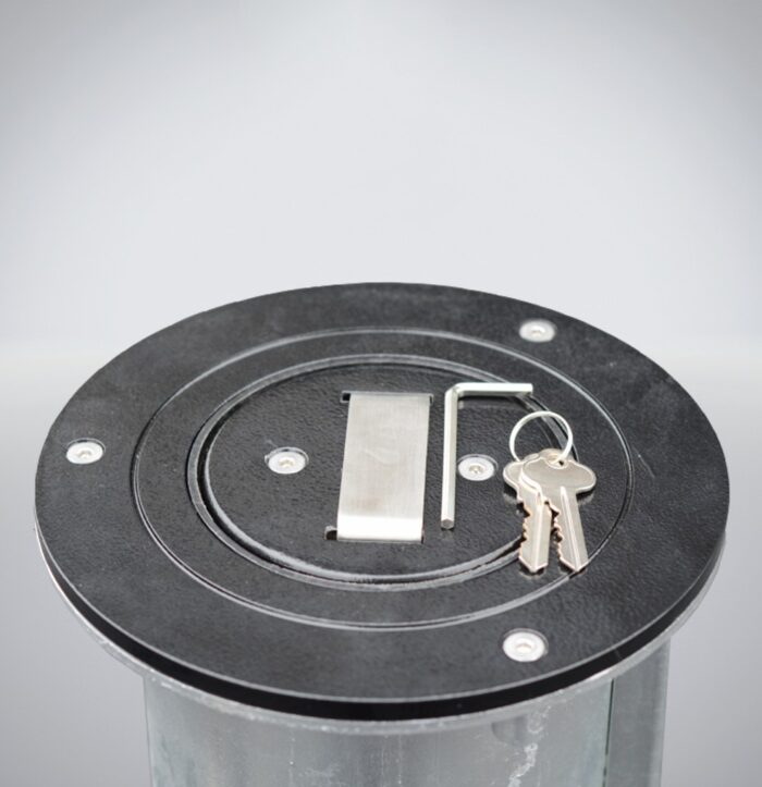 Close-up of the black base of the 114 mm Telescopic Bollard - Keylock, showing keys and tools used to operate the lifting mechanism.