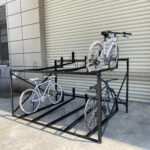 Black fixed two-tier bike rack with 10 slots installed in an outdoor public space.