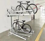 Gas Assist Double Decker Bike Rack, black bicycles parked on both layers, situated in a spacious indoor area with yellow floor markings.