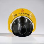 Top view of yellow D-type remote-controlled parking lock in lowered position with 'NO PARKING' sign, featuring reinforced motor and dry battery power, used to block unauthorized parking.