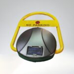 Top-down angled view of solar-powered remote parking lock, showing black base with solar panel and yellow arm with 'NO PARKING' sign and symbol.