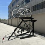 Outdoor installation of KAVASS dual-assisted bike rack holding white and black bicycles, showcasing its stability for external parking use.