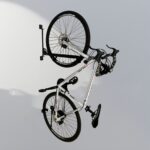 White bicycle mounted on Swing Wall Mount Bike Rack, showing space-saving wall installation in use.