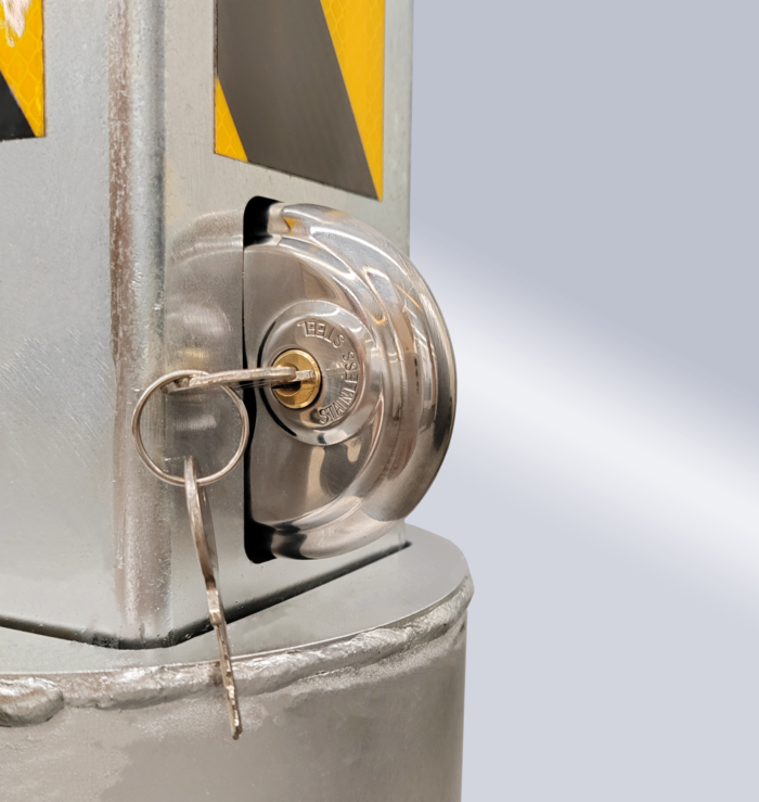 Close-up of lock on carbon steel retractable bollard, key inserted into keyhole, with 'STAINLESS' marked on the lock.