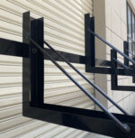 Close-up of black fixed two-tier bike rack with 10-slot structure, installed at a commercial site, without gas assist design.