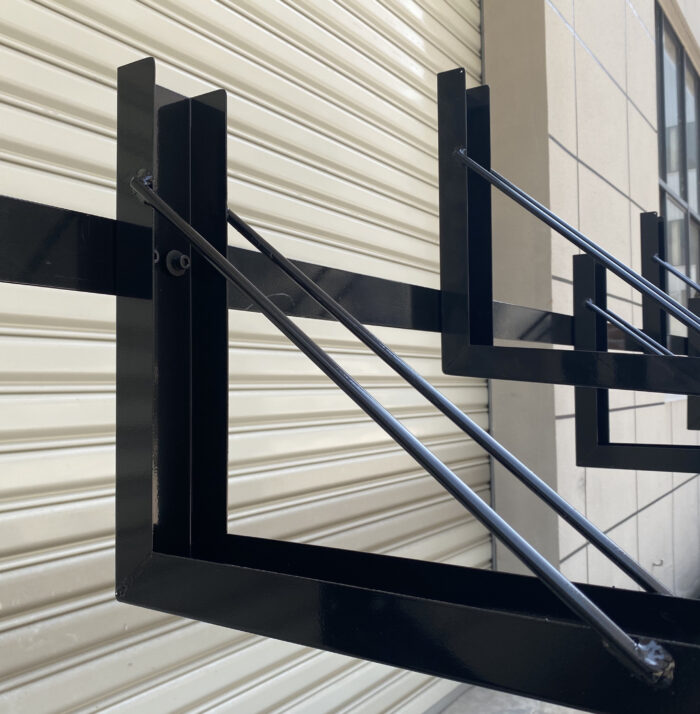 Close-up of black fixed two-tier bike rack with 10-slot structure, installed at a commercial site, without gas assist design.