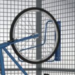 Close-up of a blue bicycle wheel fixed to a blue bracket inside the storage mesh locker, illustrating the securing method used.