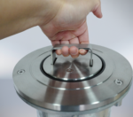 Hand operating the metal handle on the top of a stainless steel telescopic bollard, capturing the lifting operation moment.