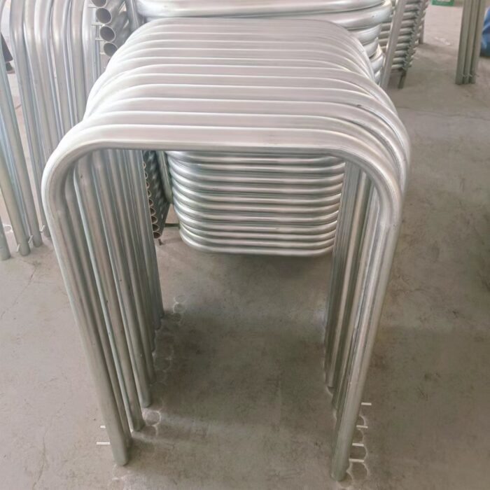 Galvanized in-ground U-bar bollards stacked in warehouse.
